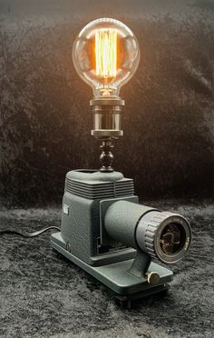 an old fashioned light bulb sitting on top of a metal stand with a camera underneath it