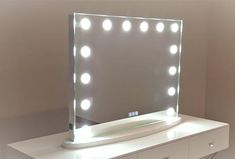 a vanity mirror sitting on top of a white dresser