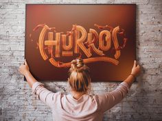 a woman holding up a sign with the word hyrros on it in front of a brick wall