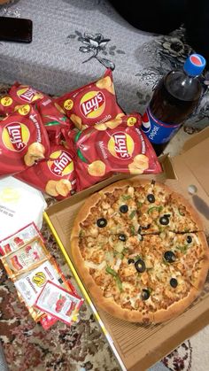 a pizza sitting on top of a table next to some chips and condiments