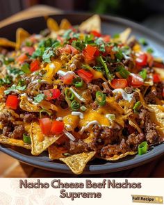 nacho cheese beef nachos with tomatoes, peppers and onions on a plate