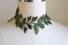 a white mannequin with green leaves on it