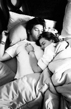 black and white photograph of two people sleeping in bed with pillows on each side of them