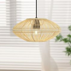 a bamboo light hanging from a ceiling in a room with blinds on the windowsill