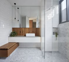 a modern bathroom with white tile and wood accents on the walls, along with a walk in shower