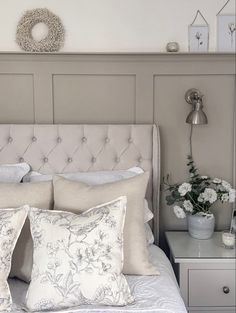 a white bed topped with lots of pillows next to a night stand and nightstands