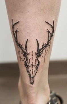 a tattoo on the leg of a woman with deer's head and antlers