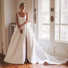 a woman in a white wedding dress leaning against a wall