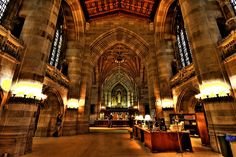 the interior of a large cathedral with stone walls and vaulted ceilings, lit by lamps