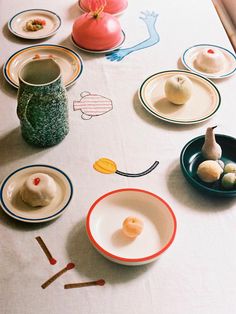 a table topped with plates and bowls filled with different types of food on top of a white table cloth