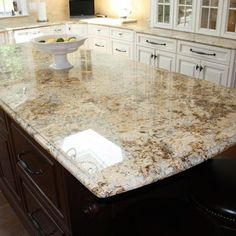 a large kitchen island with granite counter tops and white cabinets in the middle of it