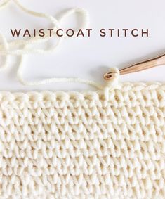 a white knitted blanket with the words daisycrafts on it and a knitting needle