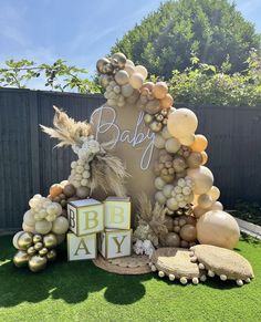 a baby shower with balloons and decorations in the shape of a arch on fake grass