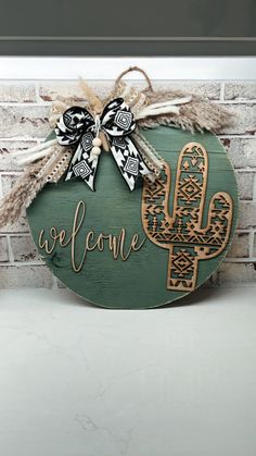 a wooden sign that says welcome with a cactus on it