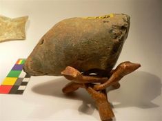 an old rock sitting on top of a wooden stand next to a piece of art