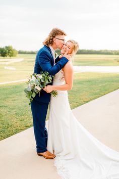 a bride and groom embracing each other in front of a golf course at their wedding