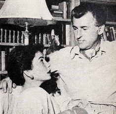 an old black and white photo of a man helping a woman put on her hair