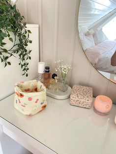 a white desk topped with a mirror next to a vase filled with flowers and candles