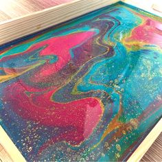 an abstract painting is being displayed on a wooden surface with paint splattered all over it