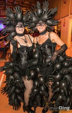 two women dressed in black are posing for the camera with large balloons on their heads