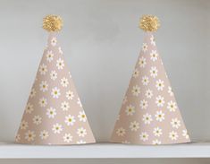 two paper hats with flowers on them sitting on a shelf