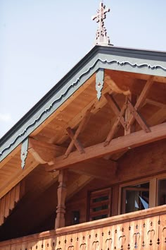 the top of a wooden building with a cross on it's roof and windows