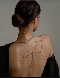 the back of a woman's neck has a tattoo on it, and she is wearing a black dress