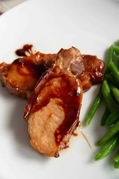 some meat and green beans on a white plate