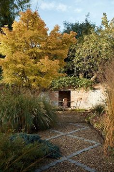 a stone path leading to a small building surrounded by trees and bushes with yellow leaves