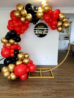 the balloon arch is decorated with black, gold and red balloons