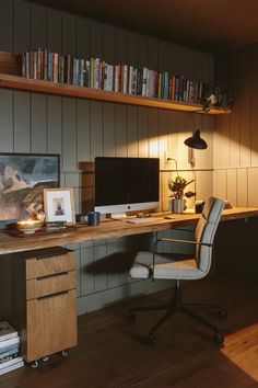 a desk with a computer on top of it in front of a bookshelf