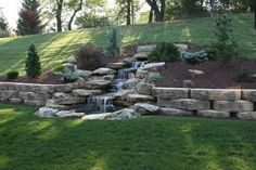 a small waterfall in the middle of a grassy area