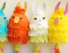 three llamas are hanging on the wall with colorful feathers attached to their heads