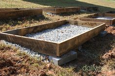 several wooden boxes with gravel in them on the ground next to some grass and trees