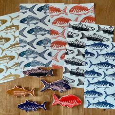 five different colored fish magnets sitting on top of a wooden table