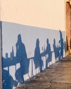 shadows cast on the side of a building as people sit at a table