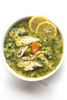 a white bowl filled with chicken, broccoli and lemons on top of a table