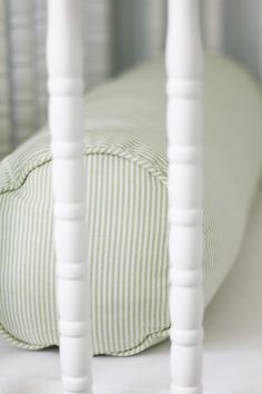 a close up of a pillow on a bed with white wooden posts and a green striped pillow