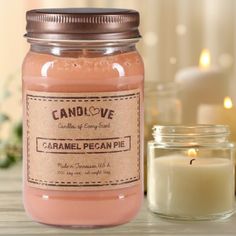 a candle sitting next to a jar filled with some kind of pink colored liquid on a table