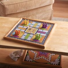 a wooden table topped with colorful tiles on top of a hard wood floor next to a couch