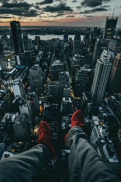 a person standing on top of a tall building with their feet up in the air