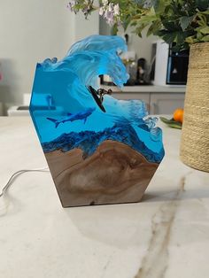 Introducing our stunning Ocean Wave LED Lamp featuring a surfer and a shark, handcrafted from epoxy resin and wood. This mesmerizing marine biology-inspired night light creates a warm, inviting glow, perfect for any bedroom, living room, or office decor. The intricate details of the shark and surfer bring the ocean to life, making it an ideal beach lover gift for him, her, dad, or any ocean enthusiast. Crafted with love and attention to detail, this unique and rustic lamp is made from high-quali Marine Biology Room Decor, Biology Bedroom, Ocean Office, Ocean Themed Bedroom Night Lights, Whale Shark Lamp, Ocean Kids Room, Ocean Baby Rooms, Ocean Led Light, Epoxy Resin Night Lamp