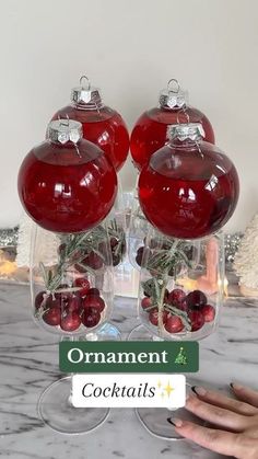 two wine glasses filled with red ornaments on top of a marble counter next to a christmas tree