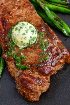 a steak and asparagus on a black plate with some sauce in the middle