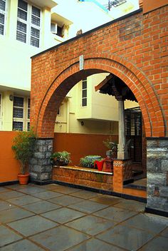 an arched brick building with potted plants on the outside and in between it's walls