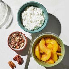 three bowls filled with fruit and nuts next to some yogurt on a table