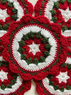 four crocheted coasters with white and green designs on them are arranged in the shape of snowflakes