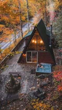 an aerial view of a cabin in the woods with a hot tub and fire pit