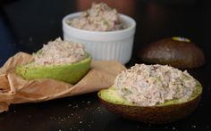 two avocados filled with tuna salad on top of a table next to a bag