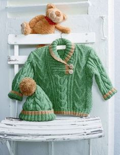 a teddy bear sitting on top of a chair next to a green sweater and hat